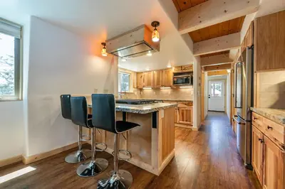 a kitchen with wooden cabinets and a counter with chairs at 10th Mountain Home - 4BR Tahoe Donner w Hot Tub, HOA amenities! in Truckee