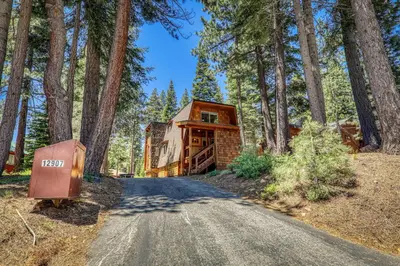 a house in the woods with a driveway at 10th Mountain Home - 4BR Tahoe Donner w Hot Tub, HOA amenities! in Truckee