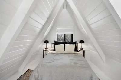 a bed in a white room with a pointed ceiling at Lake Isabella A frames in Lake Isabella