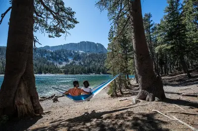 two people in a hammock on a beach with trees at Forest Creek #16 condo in Mammoth Lakes