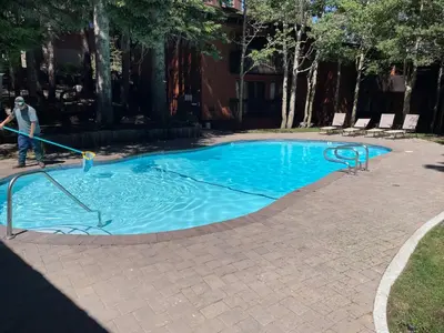 a man isblocking a swimming pool with a hose at Canyon Lodge properties by 101 Great Escapes in Mammoth Lakes