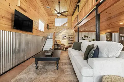 a living room with a couch and a tv on a wall at The Pine Loft | Yosemite in North Fork