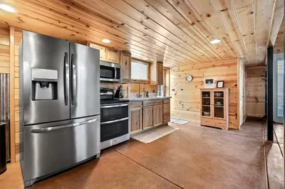 a kitchen with a stainless steel refrigerator and wooden walls at The Pine Loft | Yosemite in North Fork
