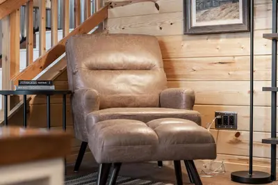 a brown chair and a stool in a room at The Pine Loft | Yosemite in North Fork