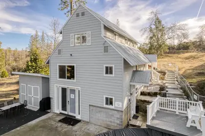 a gray house with a porch and stairs at The Pine Loft | Yosemite in North Fork