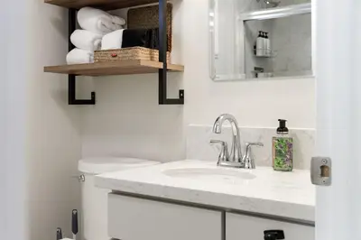 a bathroom with a sink and a toilet and a mirror at Mountain View Apartment in North Fork