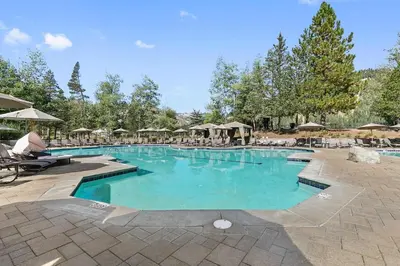 a large swimming pool with chairs and umbrellas at Everline Resort and Spa 1BR Suite with Fireplace in Olympic Valley