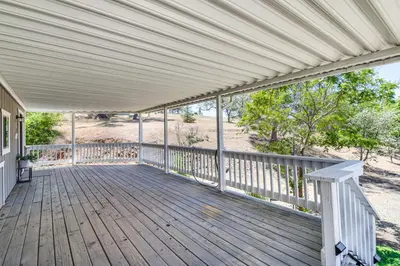 a large wooden porch with a white pergola at La Grange Home with Covered Patio and Gas Grill! in La Grange