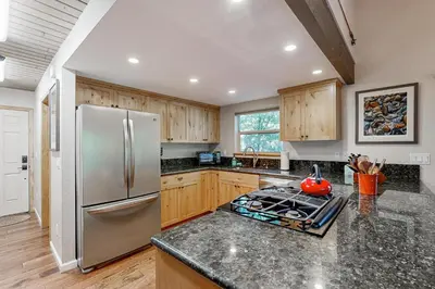a kitchen with a stainless steel refrigerator and wooden cabinets at Walk to Golf and Restaurants Serene Twain Harte Gem in Twain Harte