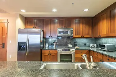 a kitchen with wooden cabinets and a stainless steel refrigerator at Big Horn Lodge 208 by East West Hospitality in Truckee