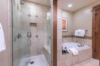 a bathroom with a tub and a shower with a glass door at Big Horn Lodge 208 by East West Hospitality in Truckee