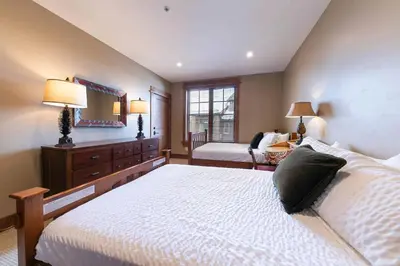 a bedroom with a bed and a dresser with a mirror at Big Horn Lodge 401 by East West Hospitality in Truckee