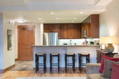 a kitchen with a bar with bar stools at Big Horn Lodge 409 by East West Hospitality in Truckee