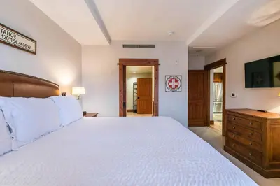 a bedroom with a large white bed and a wooden dresser at Big Horn Lodge 409 by East West Hospitality in Truckee