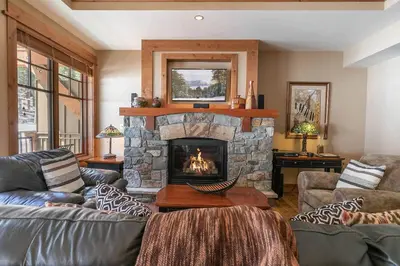 a living room with a stone fireplace and couches at Big Horn Lodge 310 by East West Hospitality in Truckee