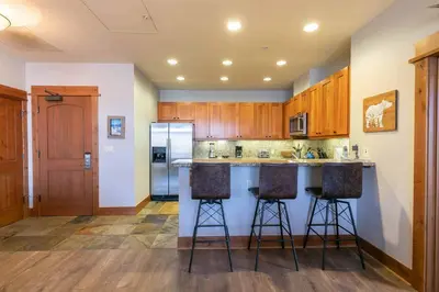 a kitchen with a counter and two bar stools at Big Horn Lodge 501 by East West Hospitality in Truckee