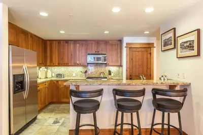 a kitchen with a counter and three bar stools at Big Horn Lodge 410 by East West Hospitality in Truckee