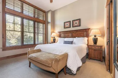 a bedroom with a large bed and a chair at Catamount Lodge 103 by East West Hospitality in Truckee