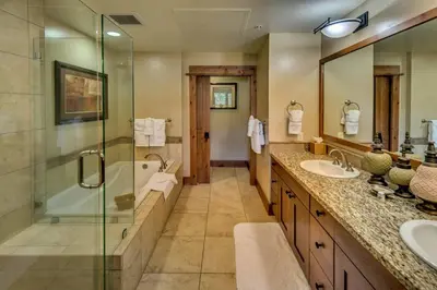 a bathroom with two sinks and a shower and a tub at Catamount Lodge 103 by East West Hospitality in Truckee