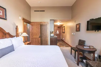 a bedroom with a bed and a table and a television at Catamount Lodge 103 by East West Hospitality in Truckee