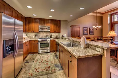 a large kitchen with wooden cabinets and stainless steel appliances at Catamount Lodge 103B by East West Hospitality in Truckee