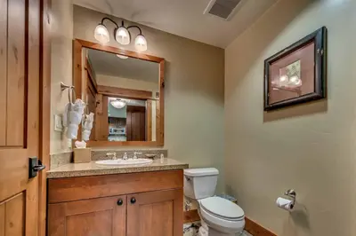 a bathroom with a toilet and a sink and a mirror at Catamount Lodge 103B by East West Hospitality in Truckee