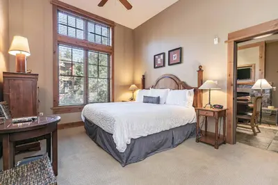 a bedroom with a bed and a desk and a window at Catamount Lodge 103A by East West Hospitality in Truckee