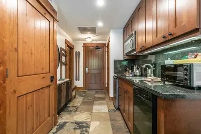 a kitchen with wooden cabinets and a counter top at Catamount Lodge 105 by East West Hospitality in Truckee
