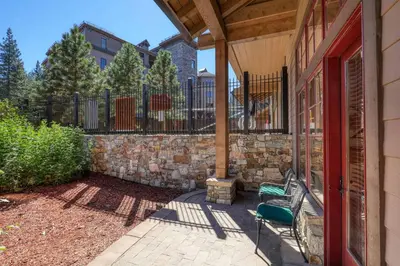 a porch with a bench and a stone wall at Catamount Lodge 105 by East West Hospitality in Truckee