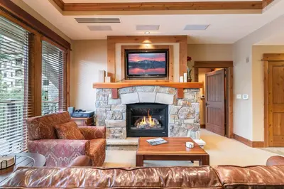 a living room with a couch and a fireplace at Catamount Lodge 201B by East West Hospitality in Truckee