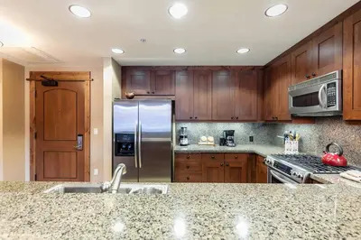 a kitchen with wooden cabinets and a stainless steel refrigerator at Catamount Lodge 201B by East West Hospitality in Truckee