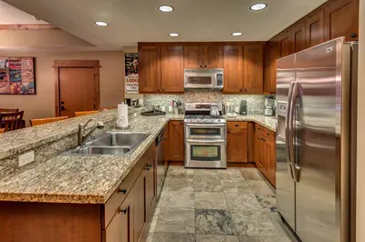 a kitchen with wooden cabinets and stainless steel appliances at Catamount Lodge 204 by East West Hospitality in Truckee