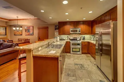 a large kitchen with wooden cabinets and stainless steel appliances at Catamount Lodge 204 by East West Hospitality in Truckee