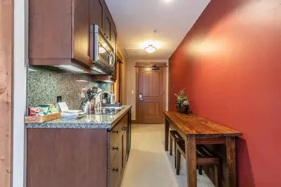 a kitchen with a counter and a wooden table at Catamount Lodge 201A by East West Hospitality in Truckee
