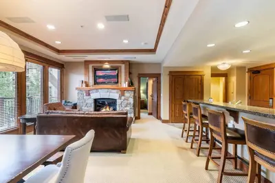 a living room with a fireplace and tables and chairs at Catamount Lodge 201 by East West Hospitality in Truckee