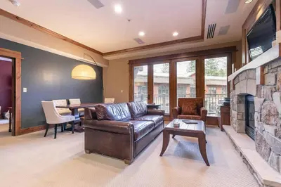 a living room with a leather couch and a fireplace at Catamount Lodge 201 by East West Hospitality in Truckee