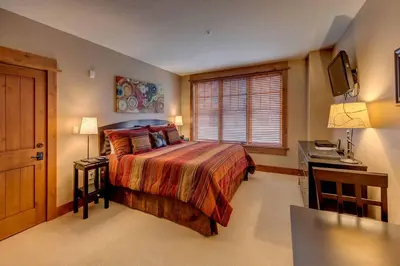 a bedroom with a bed and a desk and a television at Catamount Lodge 204A by East West Hospitality in Truckee