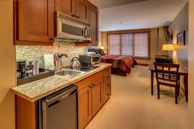 a kitchen with a sink and a bed in a room at Catamount Lodge 204A by East West Hospitality in Truckee