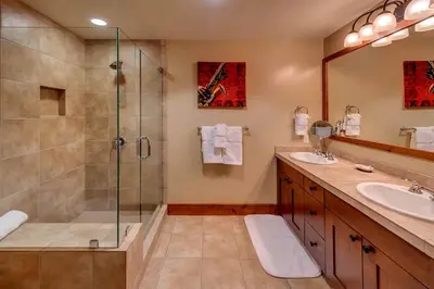 a bathroom with a glass shower and two sinks at Catamount Lodge 204A by East West Hospitality in Truckee