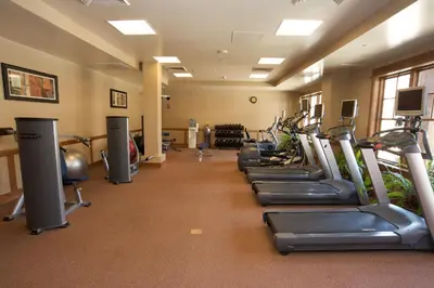 a gym with a row of treadmills and machines at Catamount Lodge 204A by East West Hospitality in Truckee