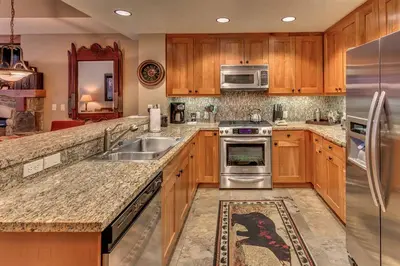a kitchen with wooden cabinets and stainless steel appliances at Catamount Lodge 211 by East West Hospitality in Truckee
