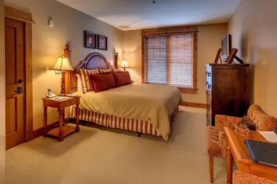 a bedroom with a bed and a table and a chair at Catamount Lodge 206A by East West Hospitality in Truckee