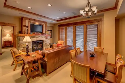 a living room with a couch and a table and a fireplace at Catamount Lodge 206B by East West Hospitality in Truckee