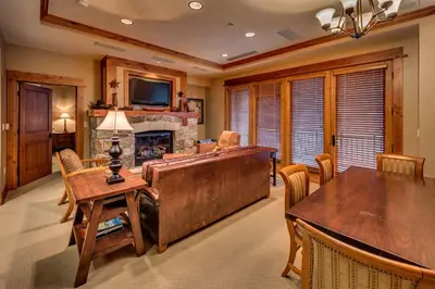 a living room with a fireplace and a table and chairs at Catamount Lodge 206B by East West Hospitality in Truckee