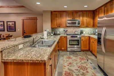 a kitchen with wooden cabinets and a stainless steel refrigerator at Catamount Lodge 206B by East West Hospitality in Truckee