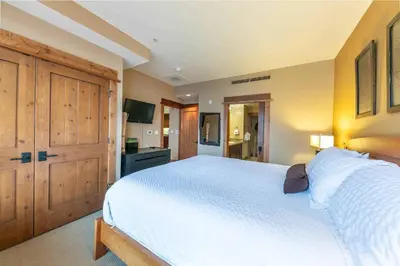 a bedroom with a large white bed and wooden cabinets at Catamount Lodge 305 by East West Hospitality in Truckee