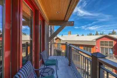 a balcony with two chairs on a building at Catamount Lodge 301 by East West Hospitality in Truckee