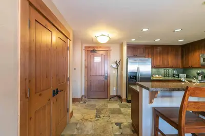 a kitchen with wooden cabinets and a refrigerator at Catamount Lodge 301 by East West Hospitality in Truckee