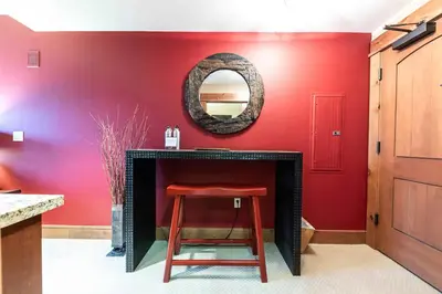 a red room with a stool and a mirror over a fireplace at Catamount Lodge 305A by East West Hospitality in Truckee