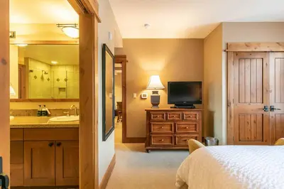 a bedroom with a bed and a television and a bathroom at Catamount Lodge 312 by East West Hospitality in Truckee